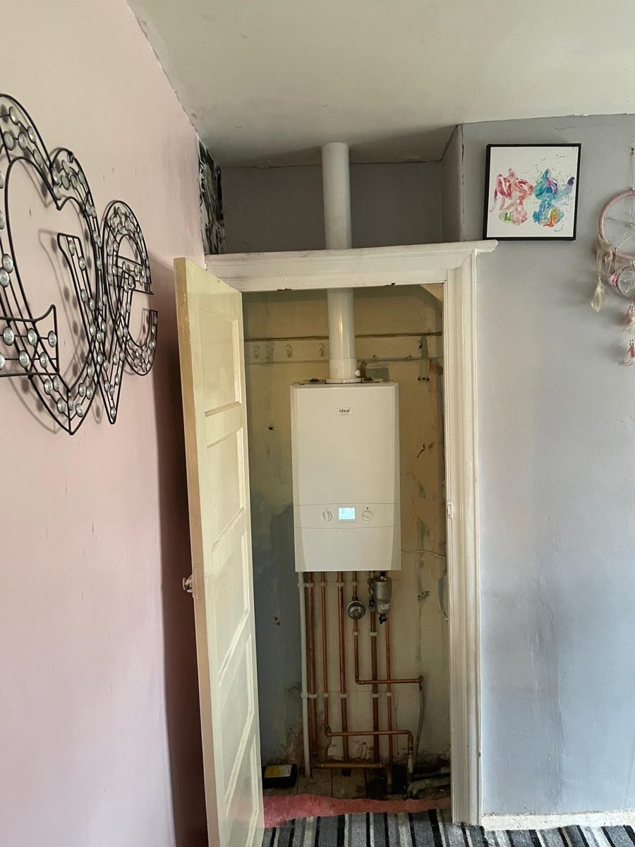 Combi boiler fitted inside a hallway cupboard with pipework run neatly to the floor
