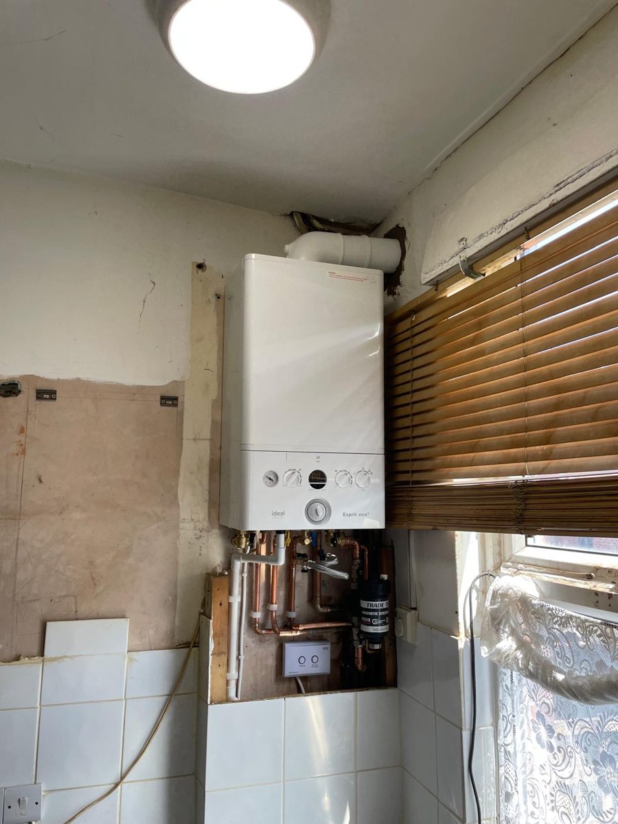 Wall-mounted combi boiler installed in a kitchen, with pipework and controls fitted