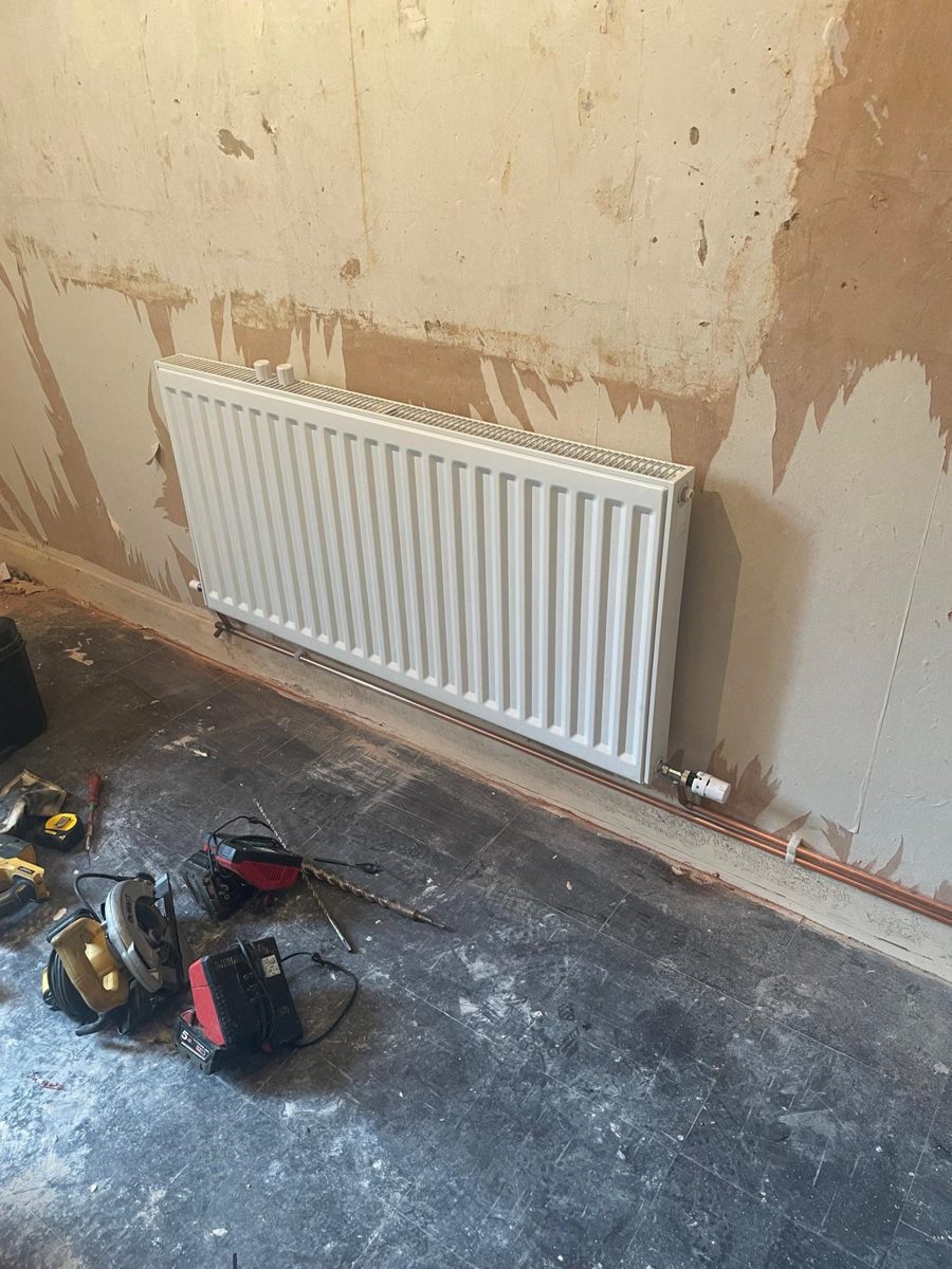 Radiator fitted in a room mid-renovation, pipework connected before decorating