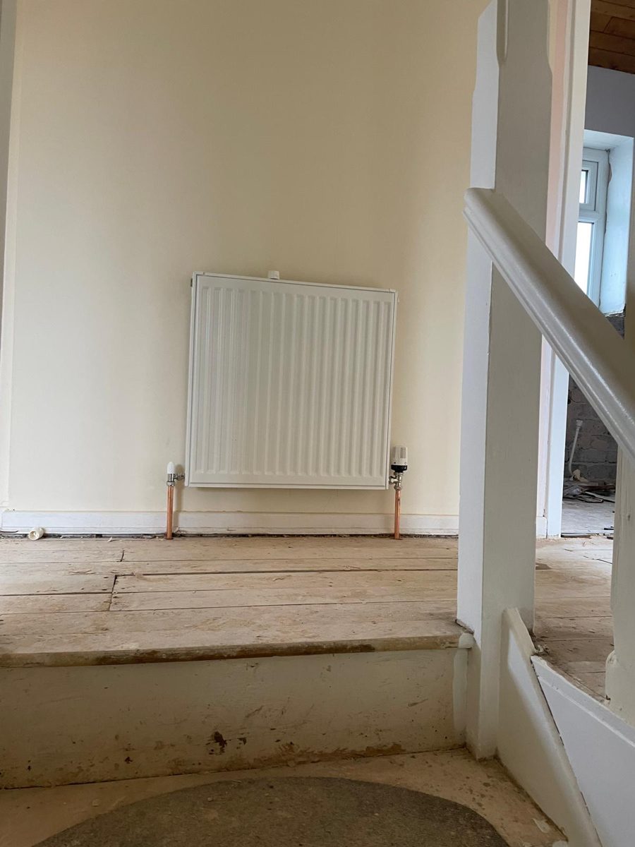 Panel radiator installed on a landing beside the stairs